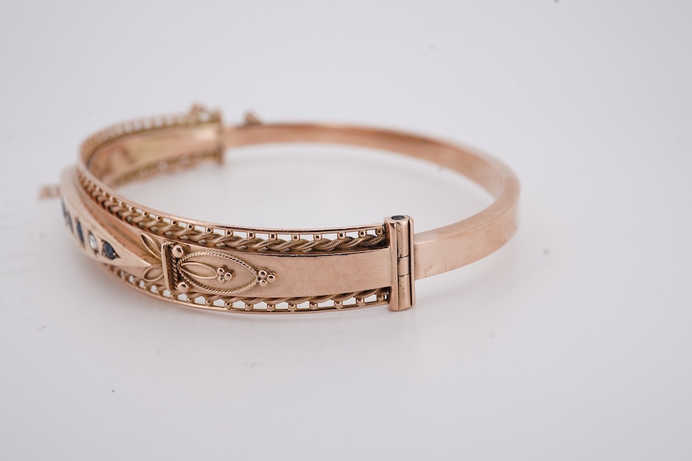 An Edwardian 9ct gold, sapphire and diamond set hinged bangle, Chester, 1909, interior diameter 57mm, gross weight 10 grams. Condition - poor